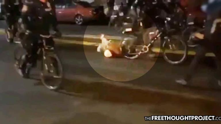 Bystanders Watch in Horror as Cop Rides Bicycle Over Man's Head as He Lies on the Ground