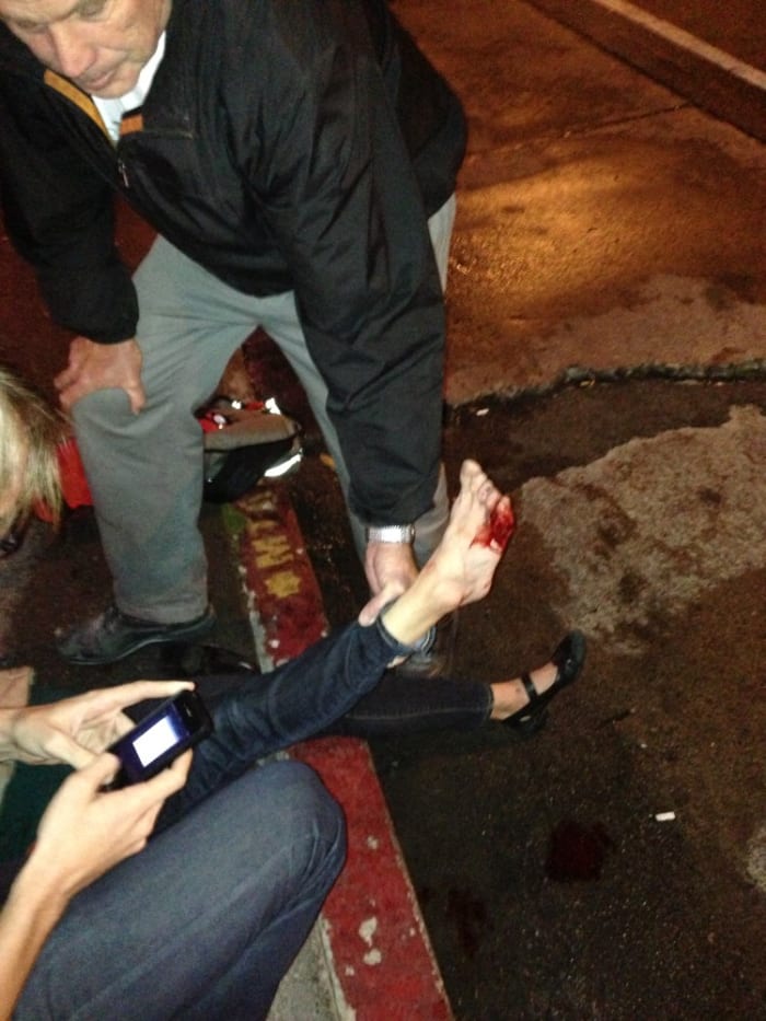 The first bystander helps Rebecca elevate her foot as Ben is preparing to take a photo per her request.