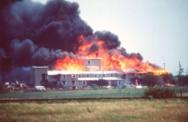 The Branch Davidians’ Mount Carmel Church burned after FBI agents and Delta Force operators pumped it full of flammable tear gas, smashed holes in the sides to vent it like a potbelly stove on the windiest day of the year, and then shot 40 mm tear gas grenades and military illumination rounds into the structure that were flammable while initially claiming they didn’t. Multiple expended 40 mm tear gas rounds, flash bang grenades and illumination rounds were found in the debris by the Texas State Rangers during their investigation. Six flash bang grenades found in the debris were mislabeled for years as silencers and/or gun parts until a subsequent investigation re-examined the evidence. An FBI airplane recorded paramilitary forces, alleged to be Delta Force Squad-B, apparently machine-gunning people trying to leave the building. Video and still photos of the massacre are below.