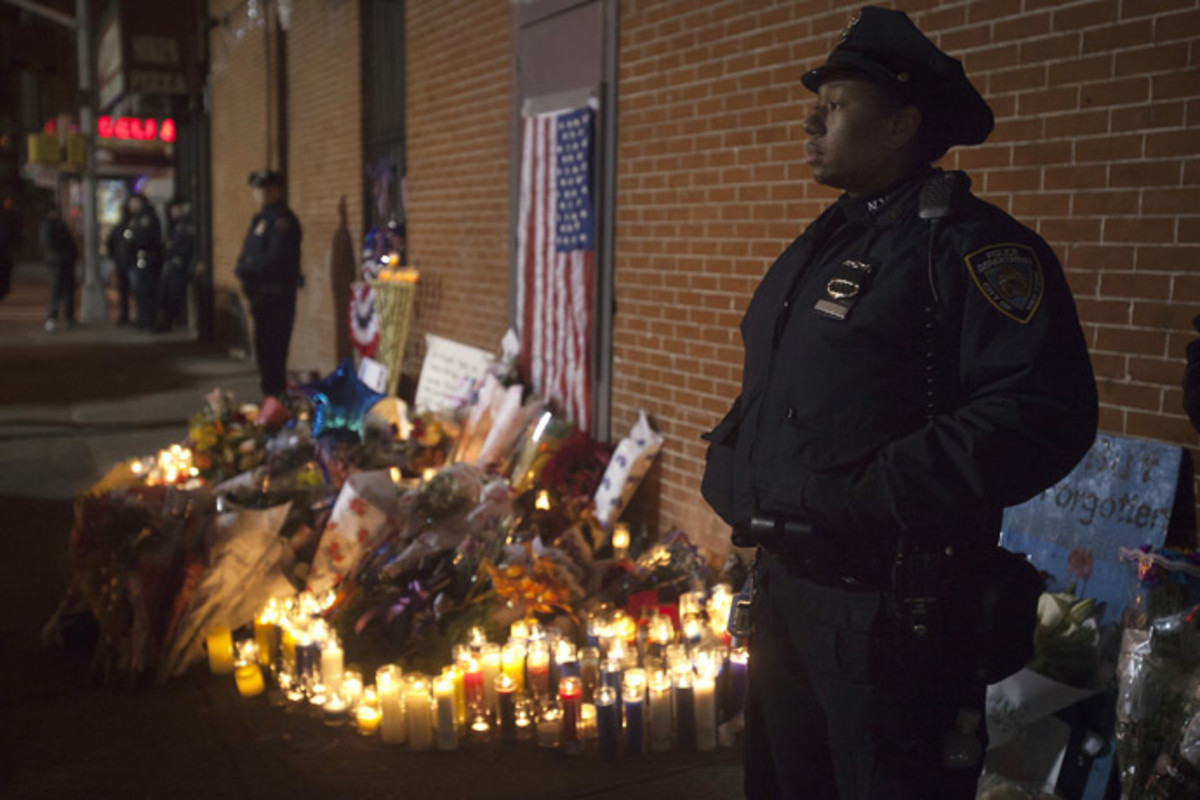 Police stand solemn during a late night vigil at a makeshift memorial at the site where two police officers were shot in the head in the Brooklyn borough of New York December 21, 2014. (Reuters/Carlo Allegri)