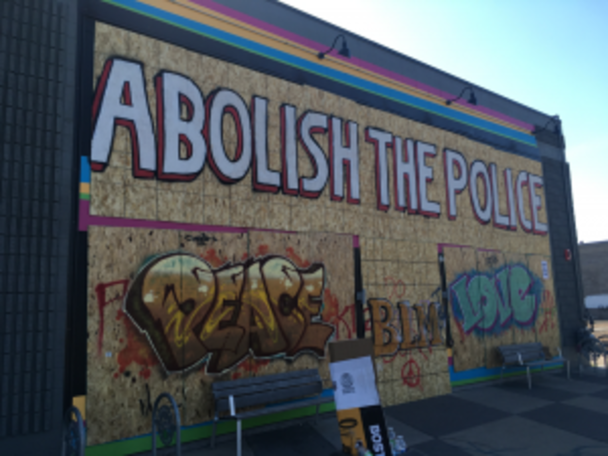 Graffiti proclaims, “Abolish the Police,” “Peace,” “BLM,” and “Love” on the wall of Moon Palace Books. Photo by Stephen Wulff.