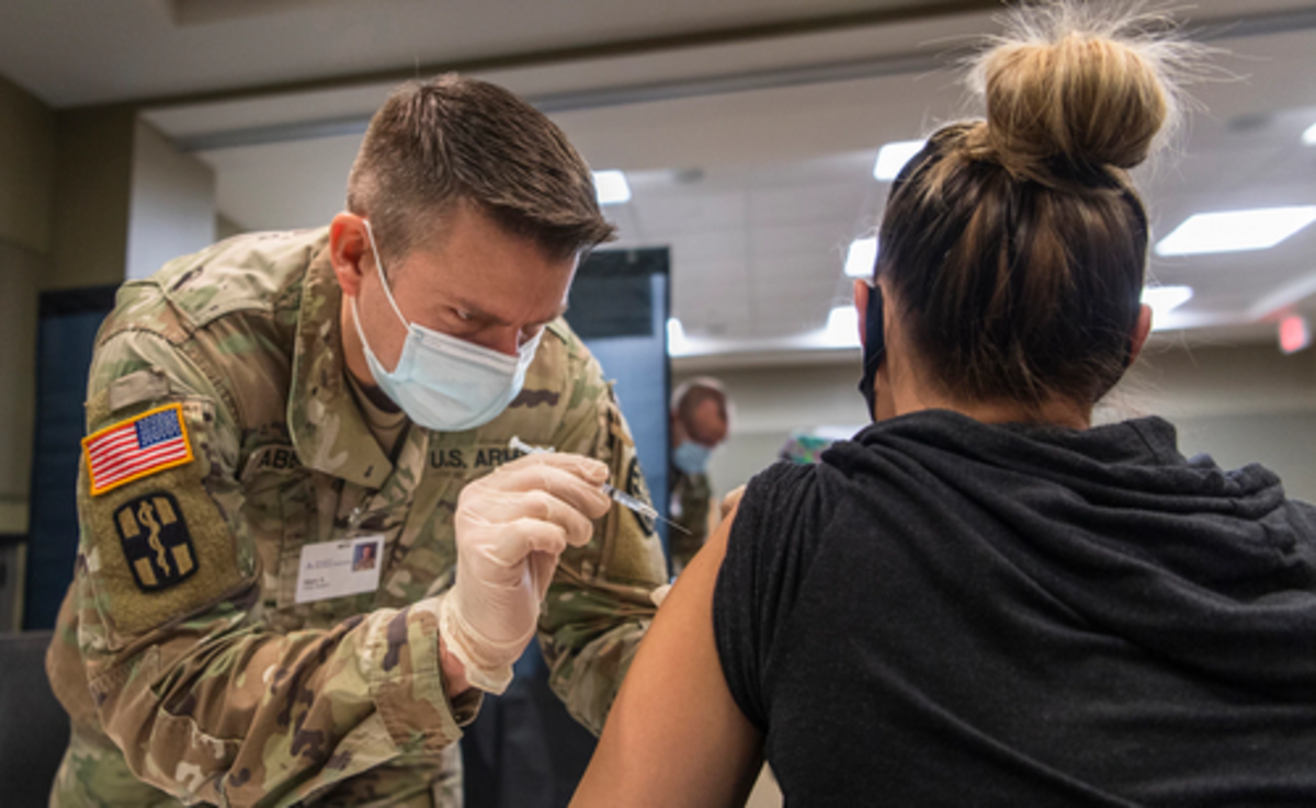 Michigan Army National Guard Sgt. Mark Abbott administers a COVID-19 vaccine